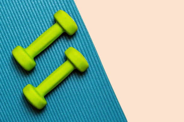 istock Two green dumbbells lay on a blue yoga mat 2172802468