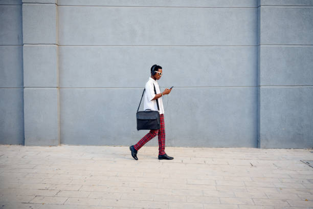 istock A professionally dressed Black businessman walking with a messenger bag while checking his phone in an urban setting 2172805402