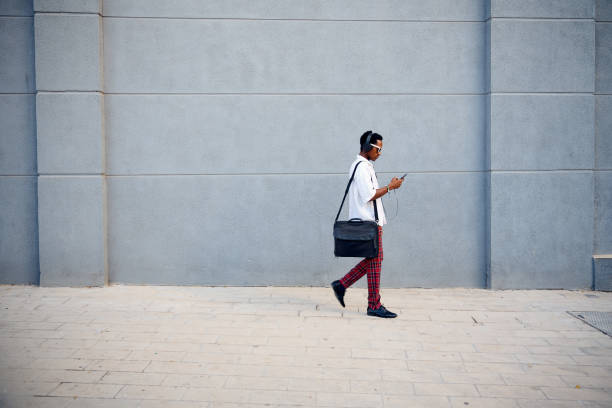 istock A professionally dressed Black businessman walking with a messenger bag while checking his phone in an urban setting 2172805409
