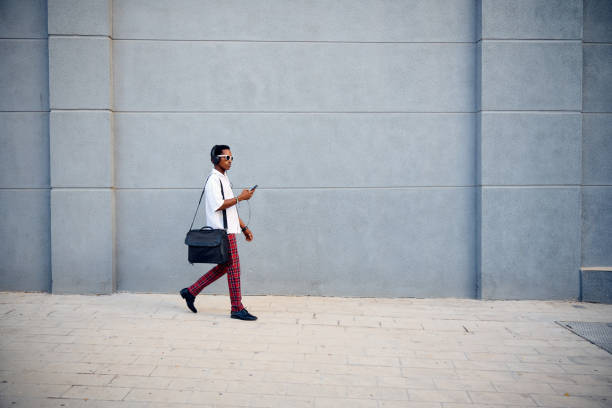 istock A professionally dressed Black businessman walking with a messenger bag while checking his phone in an urban setting 2172805410