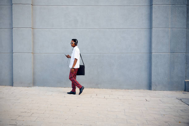 istock A professionally dressed Black businessman walking with a messenger bag while checking his phone in an urban setting 2172805422