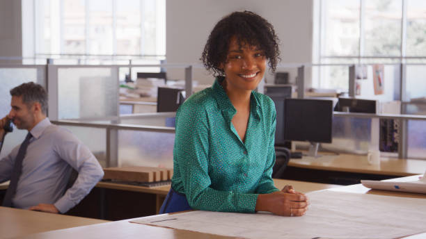 istock Portrait Of Smiling Female Architect In Modern Open Plan Office Studying Building Plans Or Drawings 2172811456