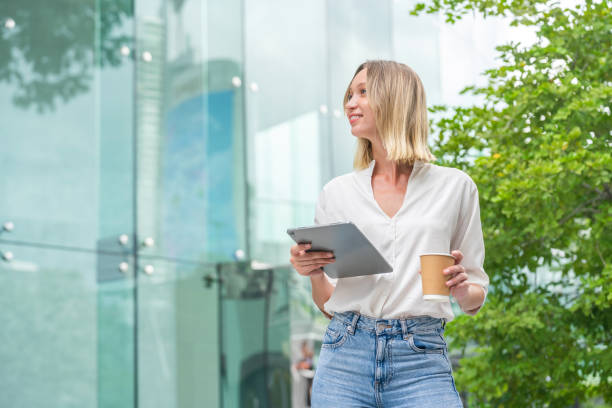 istock White Woman Holding Tablet and Coffee Cup in Urban Environment 2172811693