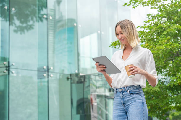 istock White Woman Using Tablet and Holding a Coffee Cup in Urban Environment 2172811798