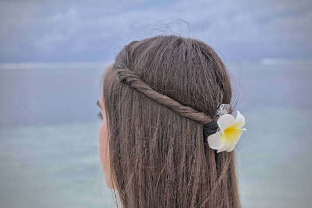 Girl with a hair floral decoration back of the head close up looking at the seaside horizon on a beach, Maldives