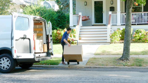 istock Male Courier Using Trolley To Deliver Package From Van To House 2172813174
