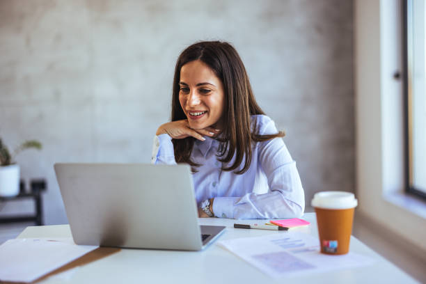 istock Smiling Woman Working Remotely on Laptop in a Bright Office 2172816118