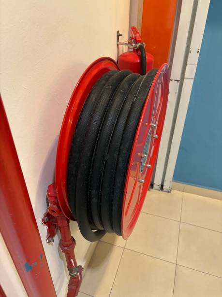 istock Red fire hose reel mounted on a wall in a building hallway. The coiled hose is ready for use, emphasizing safety, preparedness, and building fire protection systems. 2172817221