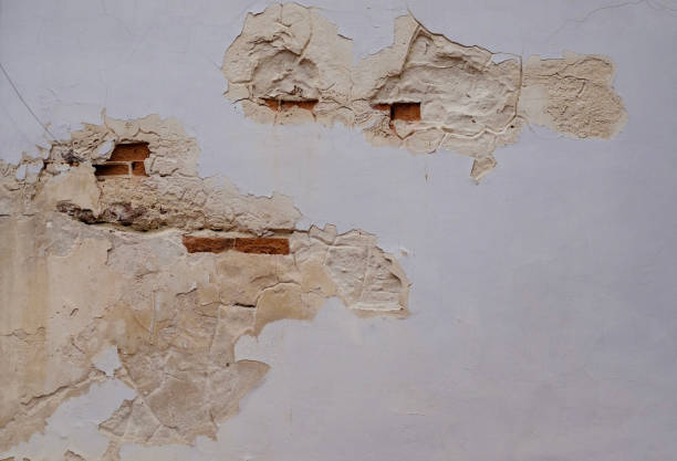 istock Textured Wall with Peeling Paint Revealing Red Brickwork Beneath Renovation Building construction 2172823048