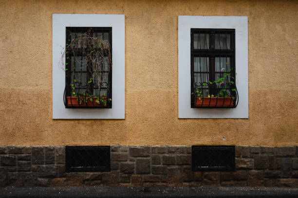 A vibrant apartment building facade featuring contrasting orange and green walls with white-framed windows. The image captures the geometric alignment and repetitive patterns of the windows, highlighting the architectural design of urban housing.