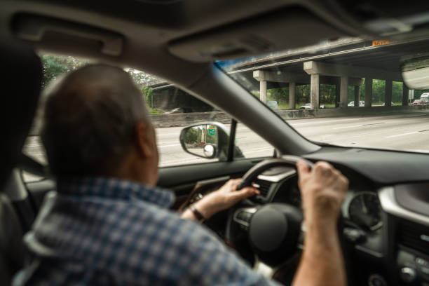 istock Senior man holding steering wheel while driving under bridge during road trip 2172845401