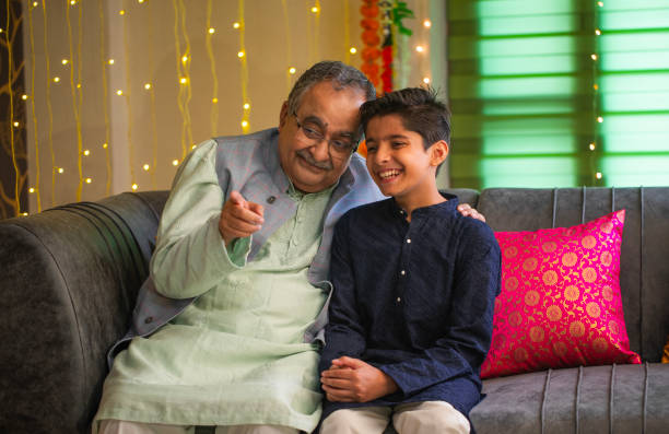 istock Grandfather and grandson talking while sitting on sofa at home 2172848827