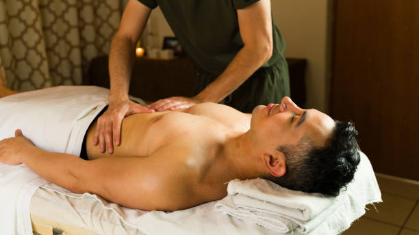 istock Relaxed man is laying on a massage table enjoying a stomach massage from a professional masseur 2172853680