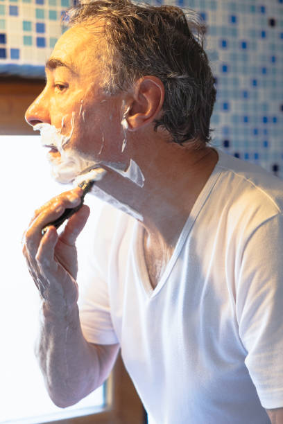 istock A middle-aged man shaves with a razor in a bathroom 2172854601