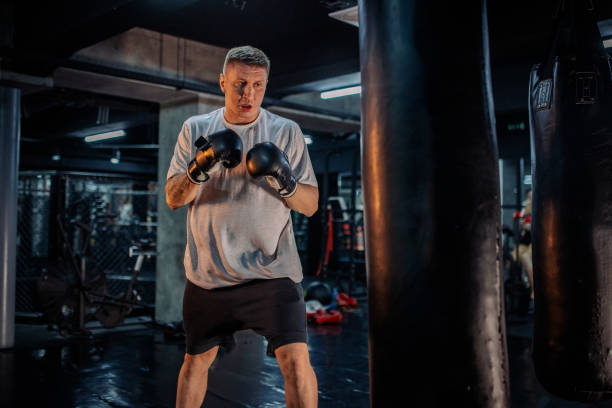 istock Boxer in fighting stance training with punching bag in gym 2172864165