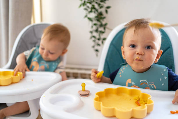 istock Cute twins having a lunch in dining room at home 2172864895