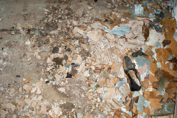 A single old fashioned black shoe stands out amongst a big pile of dirty debris inside an abandoned rundown house.