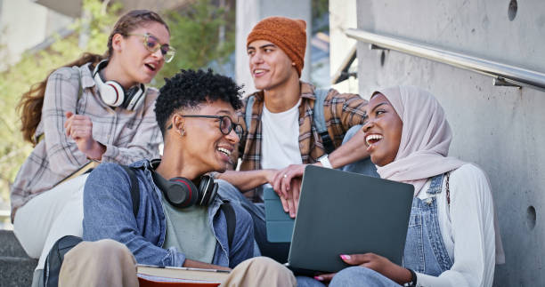 istock Group, education and laughing in campus, laptop and collaboration for research and communication with friends. Happy, online and outdoor at college, students and people with smile, stairs or backpack 2172873365