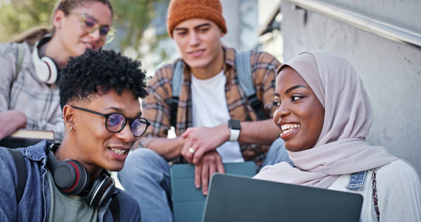 Group, reading and stairs in campus, laptop and collaboration for education and communication with friends. Happy, online and outdoor at college, students and people with smile, learning or backpack