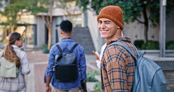University, student and man wink in portrait on campus with backpack for education, learning and scholarship. Gen z, person or happy at college for studying, knowledge or walking for research outdoor