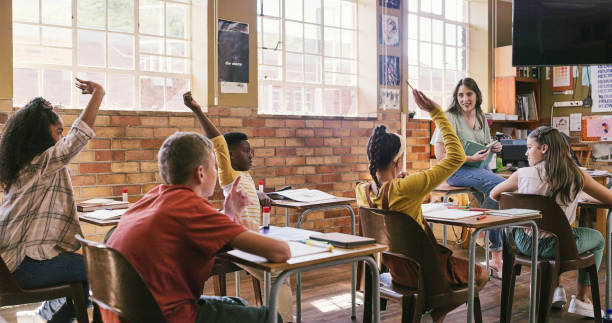 istock Smart, bright and intelligent kids in school raising hand while participating in a class room discussion with their education teacher. Confident elementary children in a classroom learning knowledge 2172874625