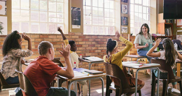 istock Class of students answering questions for teacher inside classroom at school during engaging, interesting and smart lesson. Kids thinking and raising hands while sitting at their desks with educator 2172874636