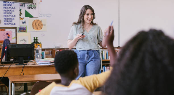 istock Teacher helping, teaching and guiding school students inside a creative classroom. Young children learning and concentrating in class with smart female educator standing in room 2172874638
