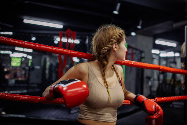 istock Woman in boxing ring resting with red gloves on ropes. 2172874920
