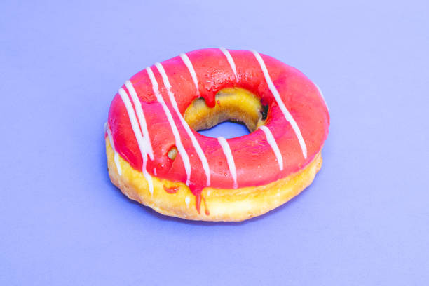 Single donut with topping laying on a blue background.