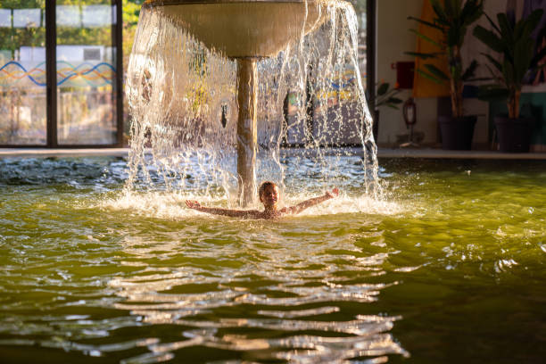istock Boy under mushroom with a waterfall in swimming pool 2172882352