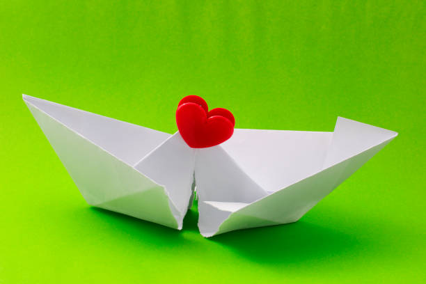 Red heart shaped clip that repairs a paper boat