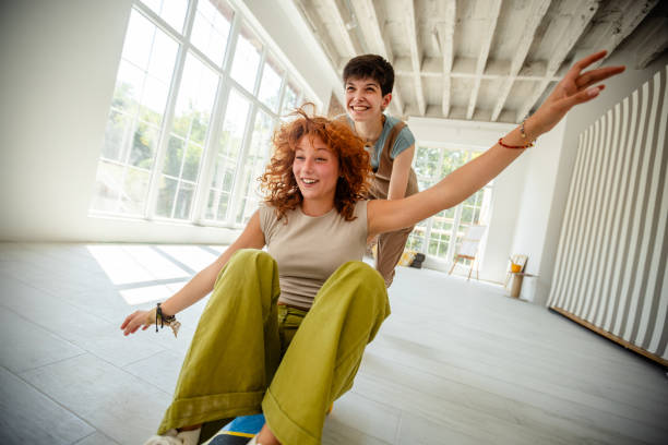 istock Friends having fun on a skateboard indoors together 2172893310