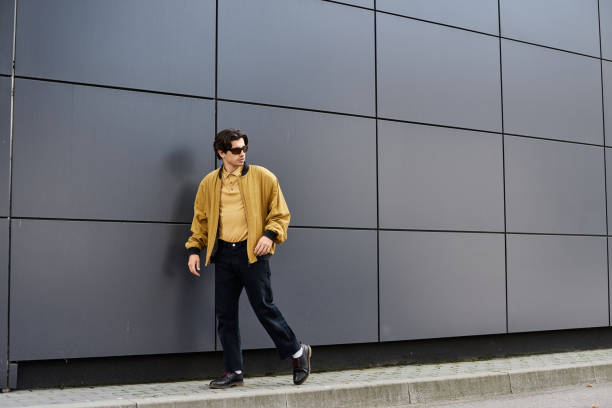Stylish young man confidently walking by modern architecture on a sunny day