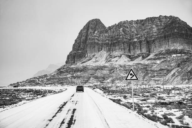 Car driving on a snowy road through a mountain range, Bachu County, Xinjiang Province, China