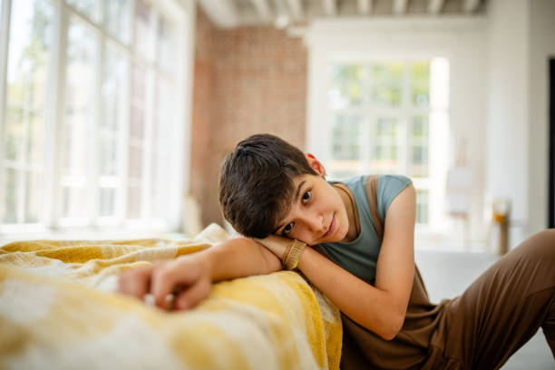 View from above of Caucasian adorable teen boy in blue jeans, checkered shirt and white t-shirt, looking at camera, lying down on a white background. Copy advertising space. Portrait of beautiful kids
