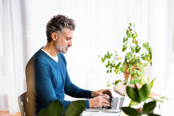 istock Handsome man working from home office, sitting at desk with laptop, smiling. Telecommuting and home office. 2172902885