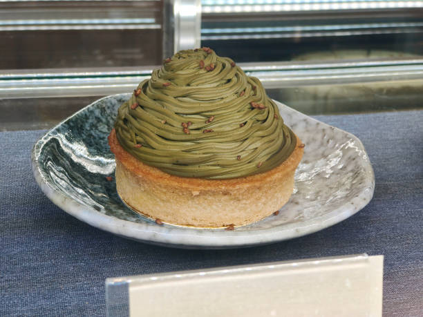 Close- up shot of Matcha Mont Blanc cake at retail display bakery. concept: matcha dessert, matcha purée in the form of vermicelli Japanese pastry, chestnut cream, green tea dessert, Mont Blanc cake, matcha sweets, gourmet dessert, Japanese confectionery, matcha flavor