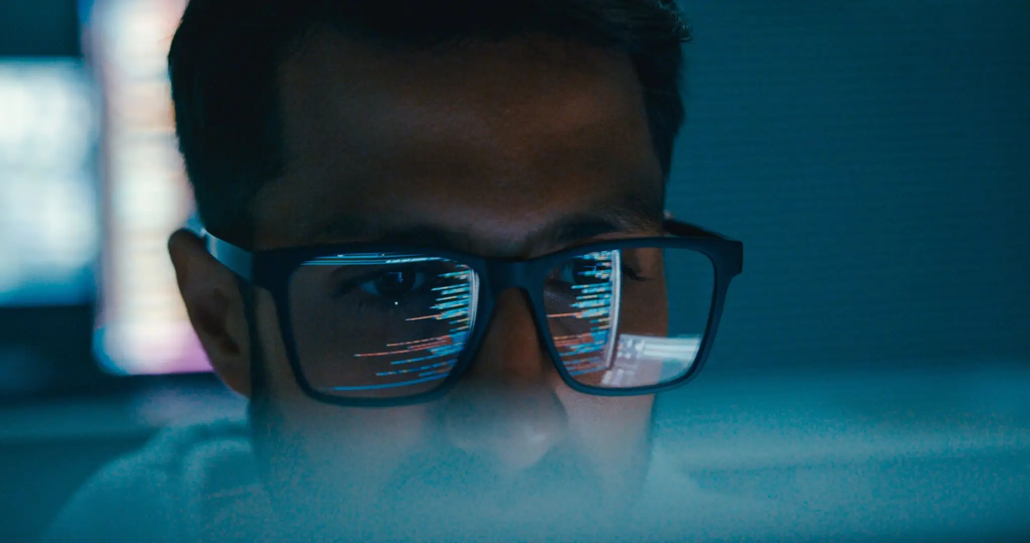 Closeup of male computer programmer works on complex software development tasks at her home office late into the night. Software developer, artificial intelligence and programming.