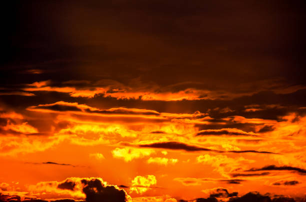 The sky is orange and cloudy. The clouds are white and the sky is dark