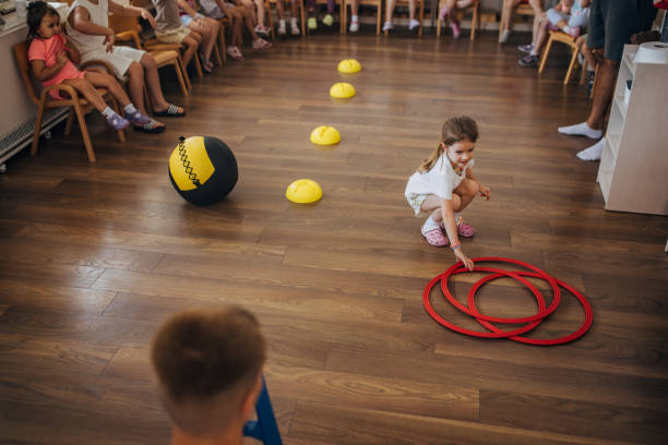 istock Child reaching for red hoops in a large play area. 2172918839