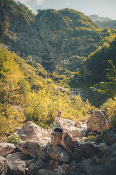 istock Young woman sits on boulder in forest 2172920956
