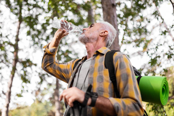 istock Smiling senior man hiking ,taking a break hydrating 2172921123