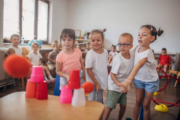 Kids engage in a target throwing game with colorful cups during a fun indoor activity session, showcasing teamwork, coordination, and lively interaction among children.