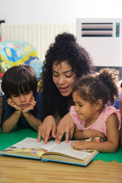 istock Teacher reading a story to her students lying on the floor 2172924938