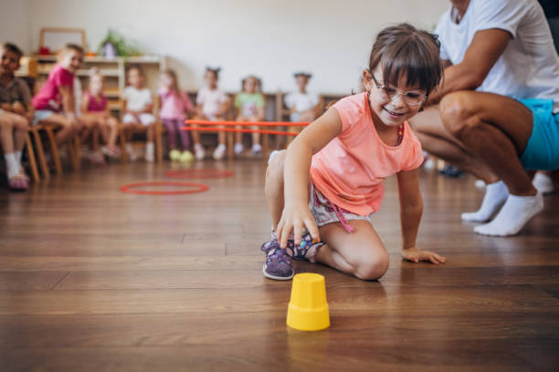 istock Girl with glasses playing on the floor with a cup. 2172928204