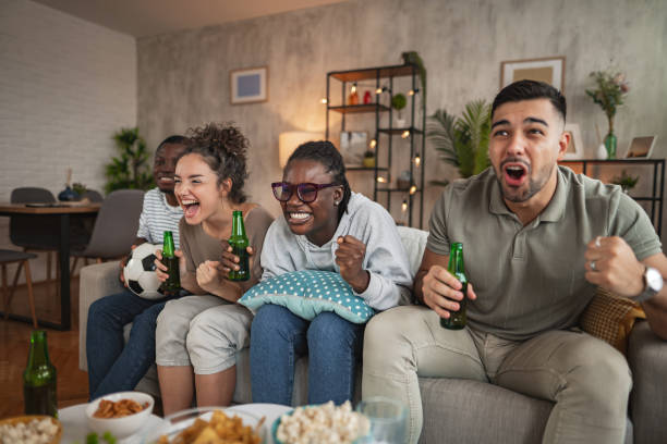istock Friends enjoying an exciting game night together while relaxing on a cozy sofa with snacks and drinks in a stylish living room 2172931906