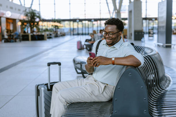 istock Young African American traveler using smartphone on the public station while waiting 2172932298