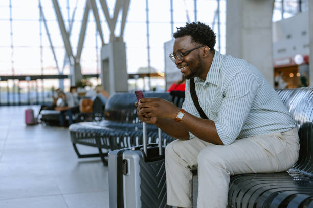 istock Young African American traveler using smartphone on the public station while waiting 2172932399