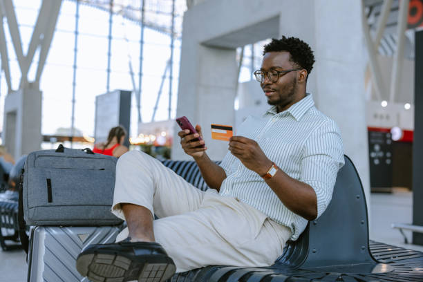 istock Man using smartphone and credit card at airport terminal 2172932456