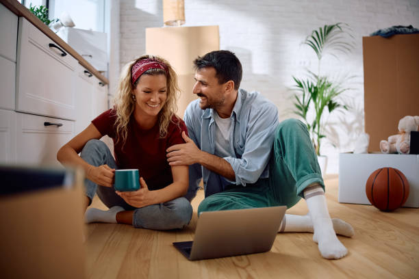 istock Happy couple talking while using laptop in their new apartment. 2172933639